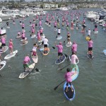 SUP boarders make their way in between boats in the bay.