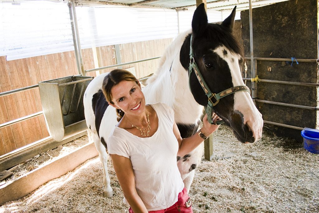 Bernadette Olsen, founder of Back Bay Therapeutic Riding Club in Newport Beach, stands next to her horse Cherokee, a 17-year-old Arab Paint horse that Olsen has had since birth. Cherokee is for more advanced riders in the program and it is considered a treat if a student gets to ride her. — Photo by Sara Hall ©