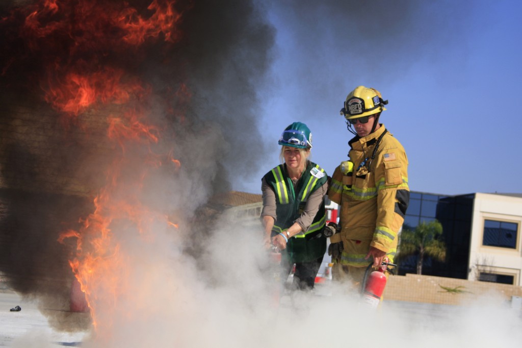 Newport Beach firefighter Jimmy Strack helps a Community Emergency Response Team volunteer extinguish a fire at Saturday's "Drill the Skills" event. — All photos by Sara Hall