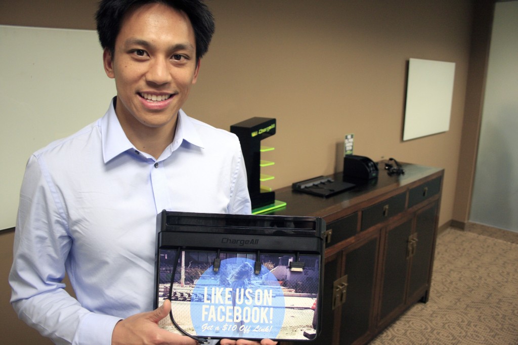 Jeffrey Maganis holds his ChargeAll charging pad , while the other models are displayed behind him in his Newport Beach office recently.