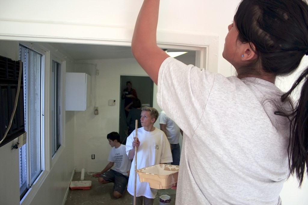 Andrea Ortega, 13, paints the SOY office on Saturday as NLYM boys work in the next room.