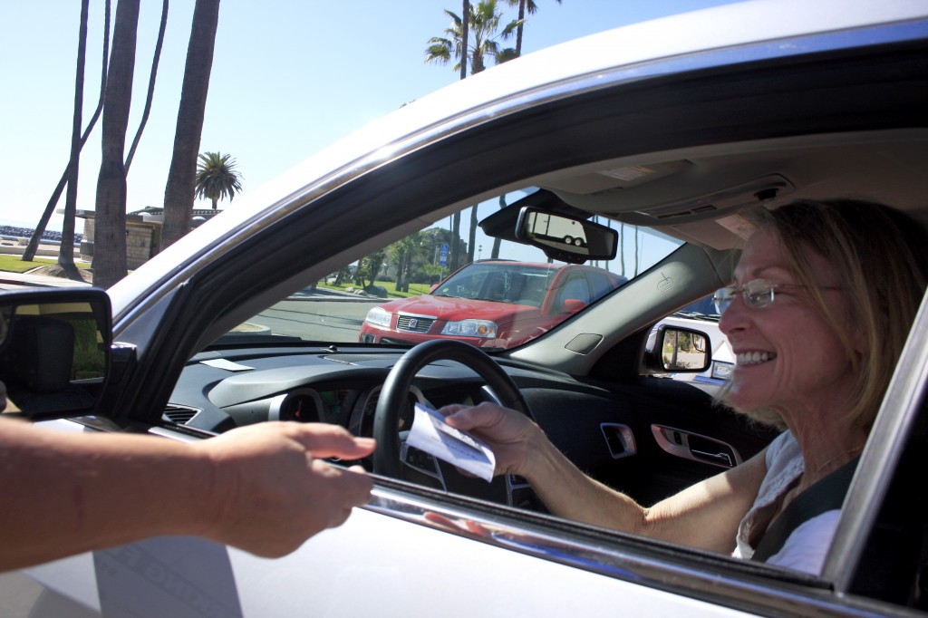 Peggy Winkler of Austin, Texas, pays for parking at the manned kiosk at Corona del Mar State Beach on Thursday. City council voted on Tuesday to replace the kiosk, along with one by Balboa Pier, with automated pay stations. 