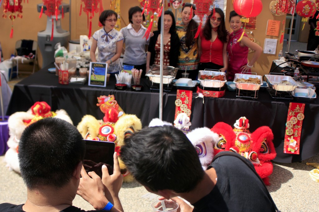 Friends and family members take photos of the China booth with the costume heads from the Ane Thanh Chinese Lion Dance group.