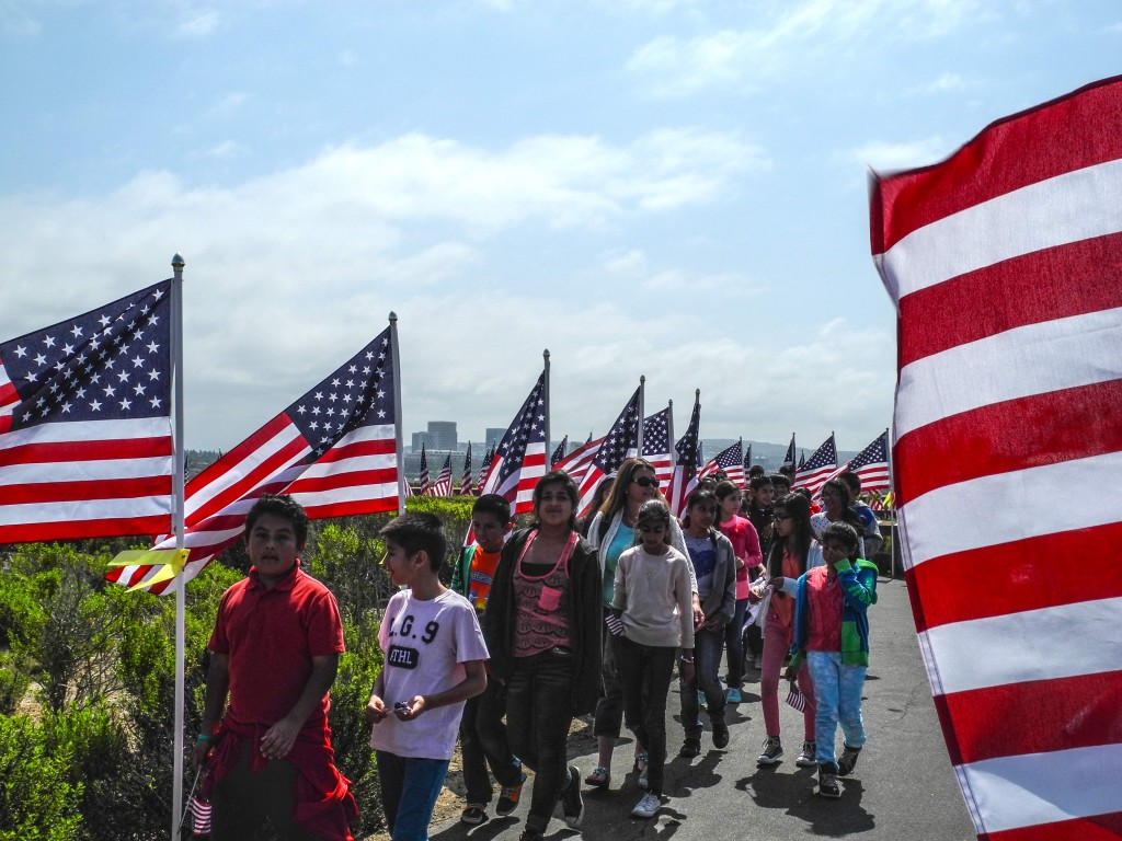 Children walking along a flag lined path.