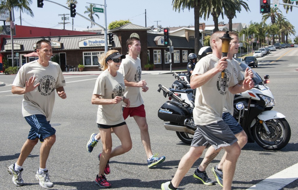 Newport Beach Police Department employees, including chief Jay Johnson (far left), running with the torch for the Special Olympics on Thursday. — Photos by Charles Weinberg