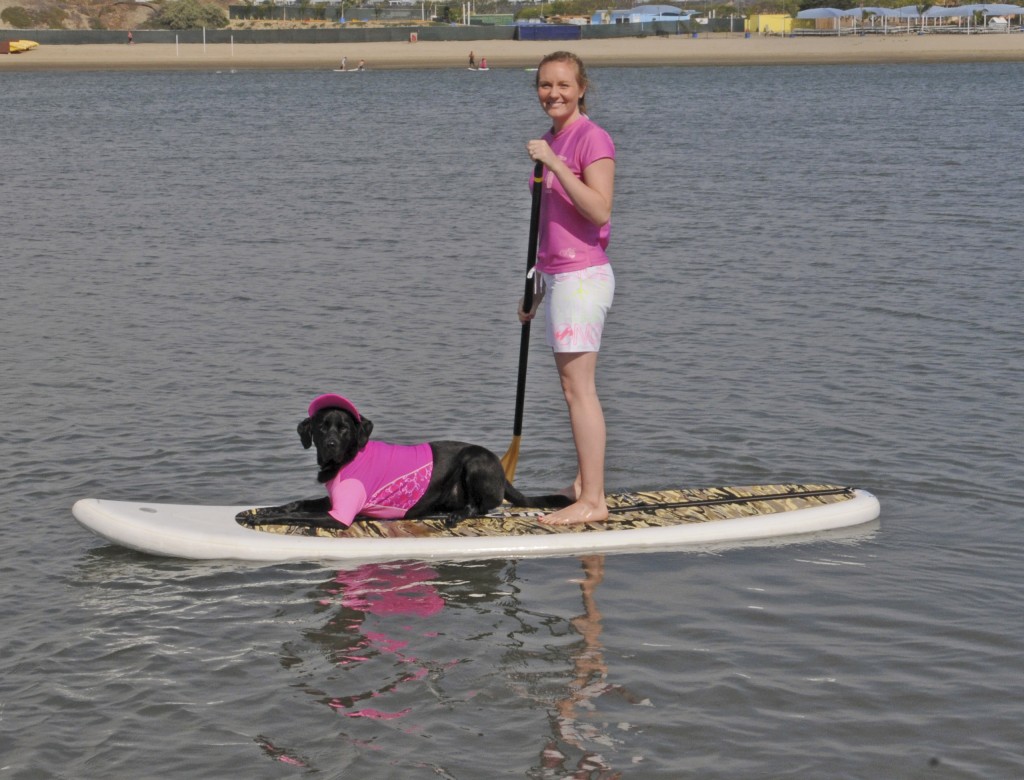 A woman and her dog, both dressed in pink for support, paddle back into Newport Dunes.