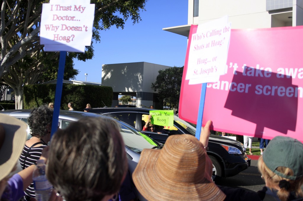 Protestors look on and chant as a Hoag supporter drives by.