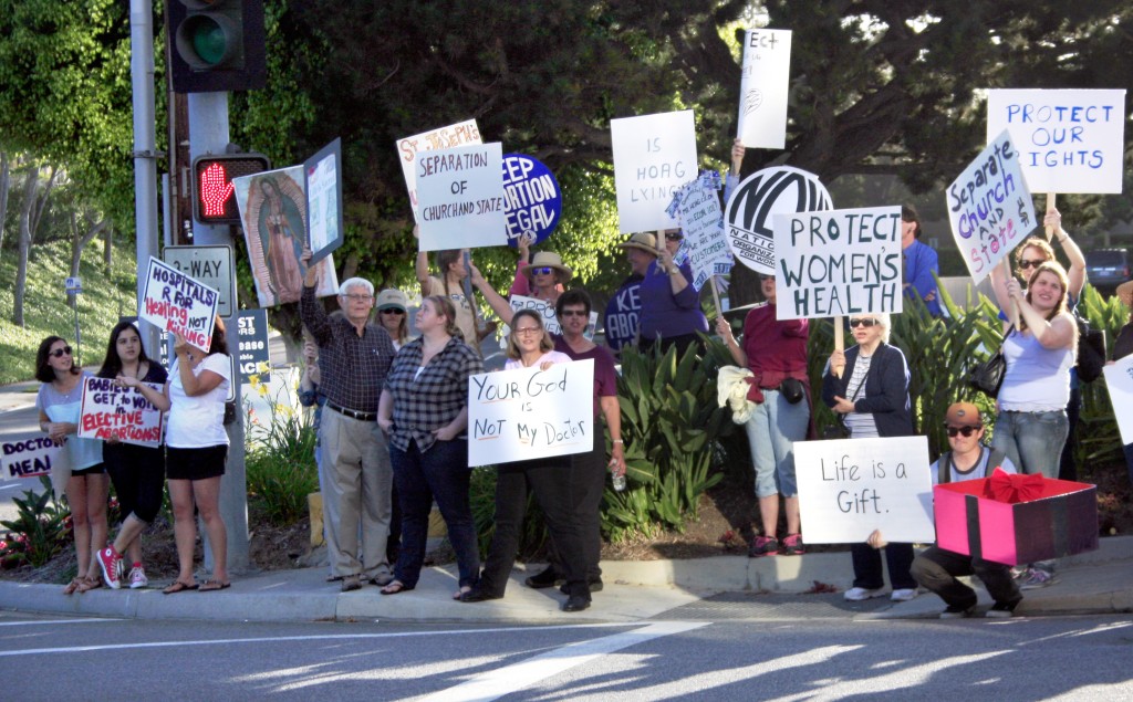 A mixture of both Hoag supporters and protestors congregate at the corner of Hospital Road and Placentia Avenue on Thursday.