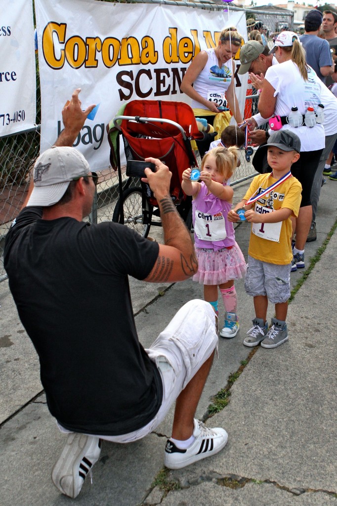 Greg Zinone gets a photo of his kids, Hudson and Hartley, with their medals after the kids race.