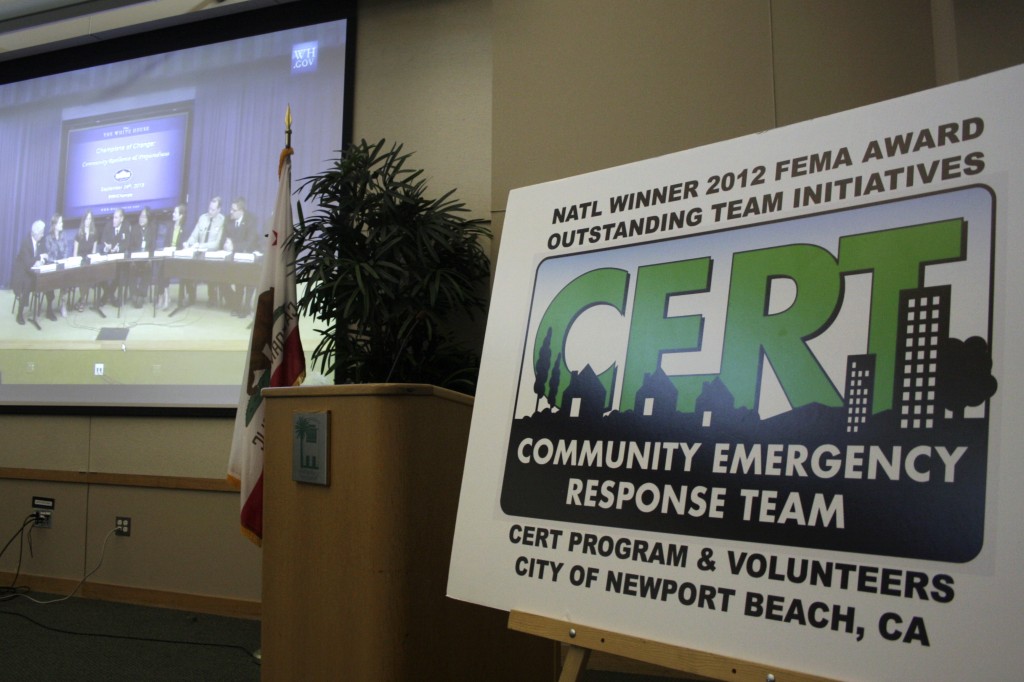 A CERT sign stands at the front of the room at the Newport Beach library as a video of the Champions of Change stream live from the White House in the background.