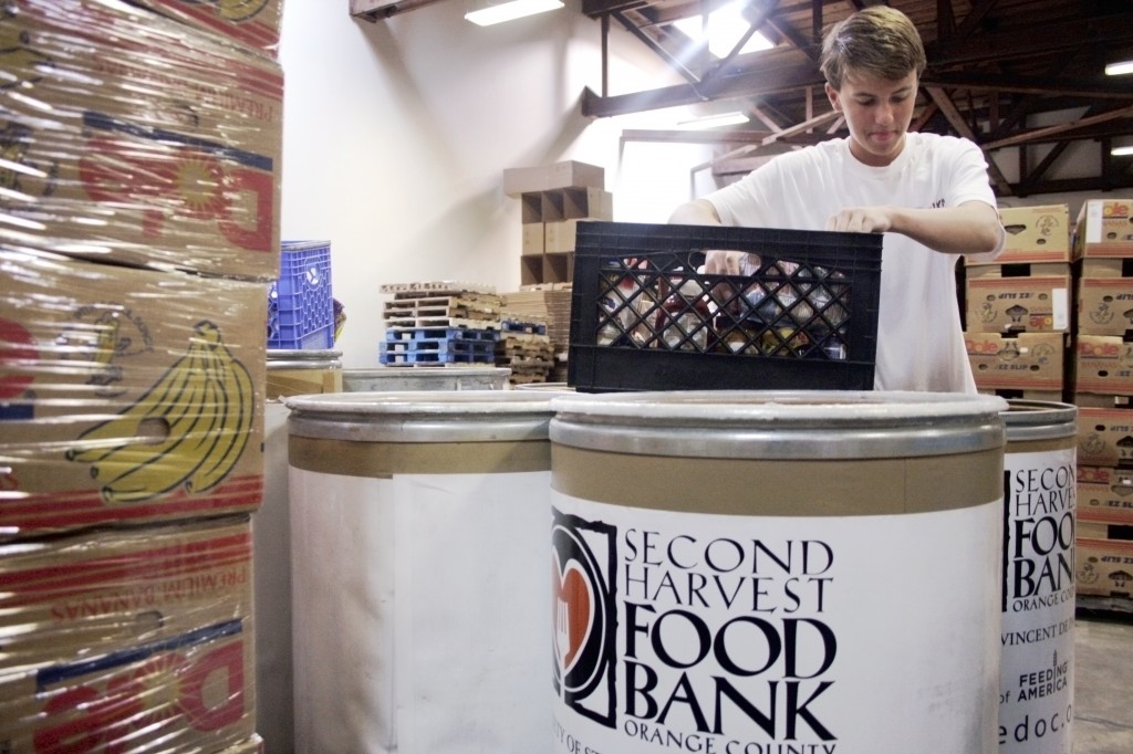 Sophomore Sean Dahl, a member of the National League of Young Men Newport-Mesa chapter, fills up a basket while sorting through donated items at the Second Harvest Food Bank of Orange County warehouse on Saturday. — All photos by Sara Hall