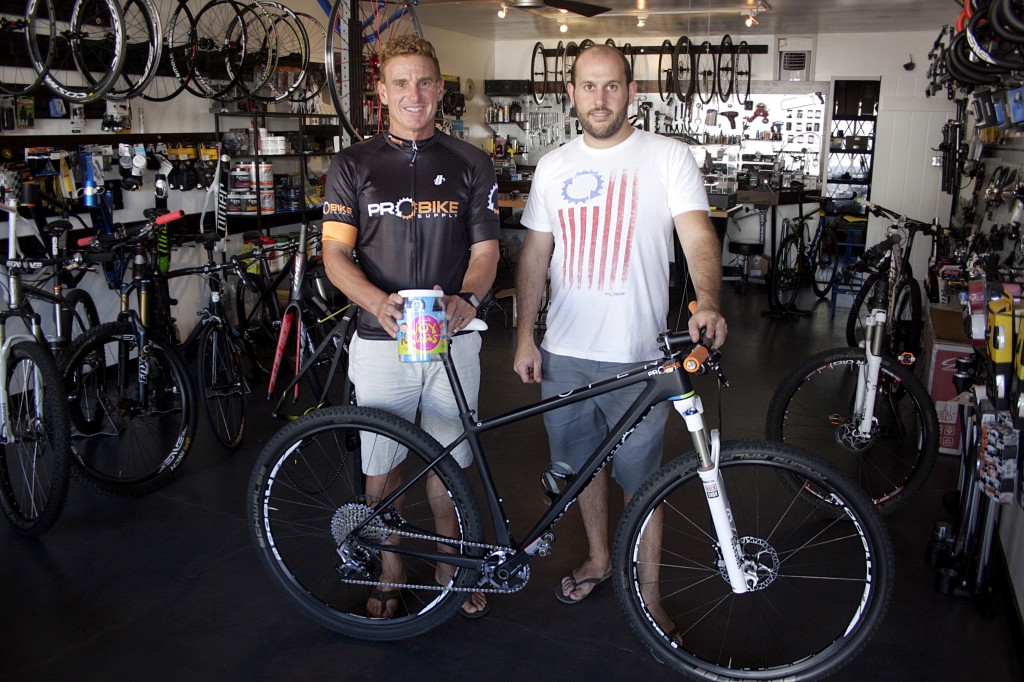 George Vitolo (left) and Mark Cohen in Cohen’s store, Pro Bike Supply in Newport Beach, with the bicycle Vitolo will ride in next month’s 12 Hours of Temecula endurance mountain bike race in an effort to raise money for charity.