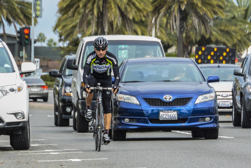 A bicyclist rides along Pacific Coast Highway among moving vehicles. — Photo by Lawrence Sherwin ©