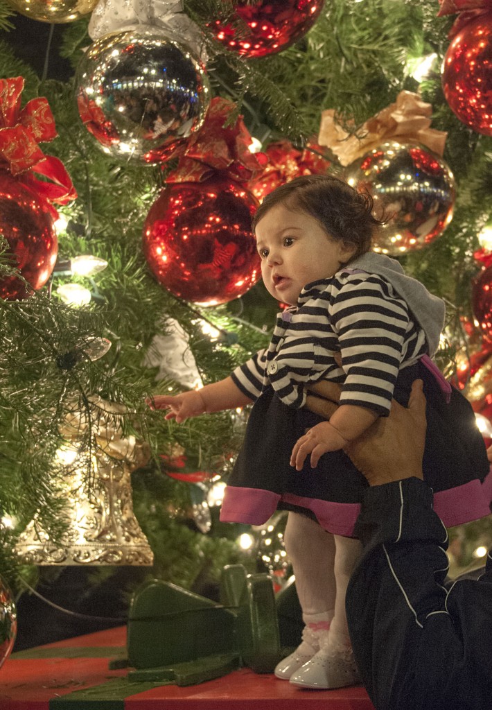 Kayleigh Bonilla, 6 months, is held up for photos in the soft glow of the lights atop the oversized presents.