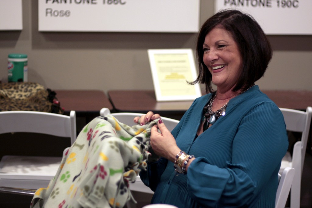 Laura Gale, a real estate agent at HÔM Sotheby’s Balboa Island office, works on a dog blanket as she talks with colleagues during the company’s Day of Giving event on Wednesday. — Photo by Sara Hall