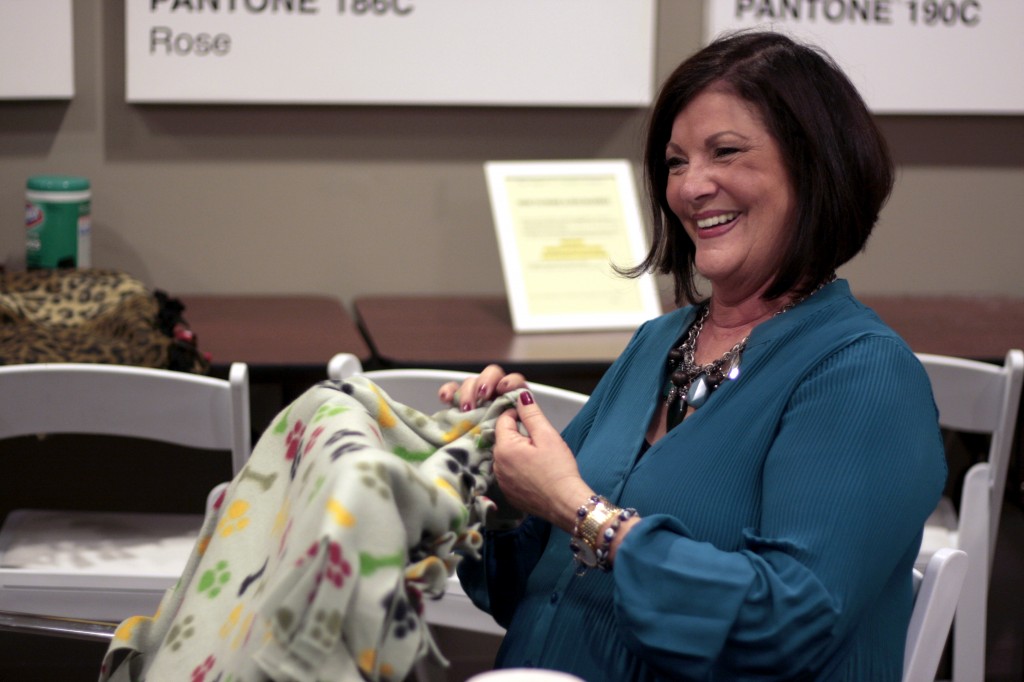 Laura Gale, a real estate agent at HÔM Sotheby’s Balboa Island office, works on a dog blanket as she talks with colleagues during the company’s Day of Giving event on Wednesday.  — Photo by Sara Hall