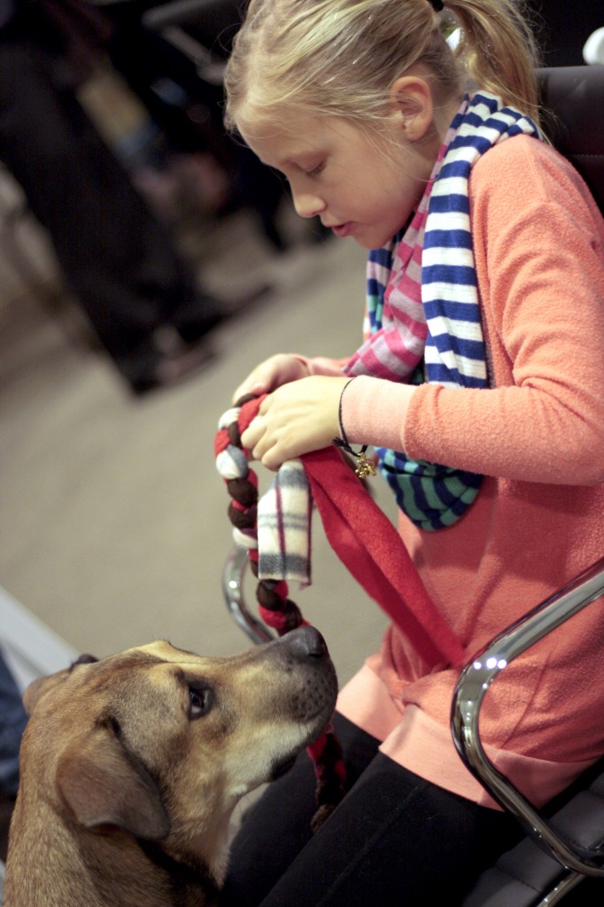 Madi Swart, 9, a fourth grader at Mariner’s Elementary School, works on a dog toy as her family’s adopted German shepherd/boxer/lab mix watches. Swart came with her mother, a HÔM Sotheby’s employee, to the event. — Photo by Sara Hall