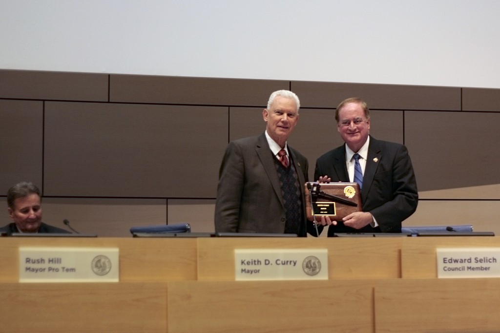 Newly elected Mayor Rush Hill presents a gavel plaque to councilman and outgoing mayor Keith Curry. Mayor Pro Tem Ed Selich looks on from the background.