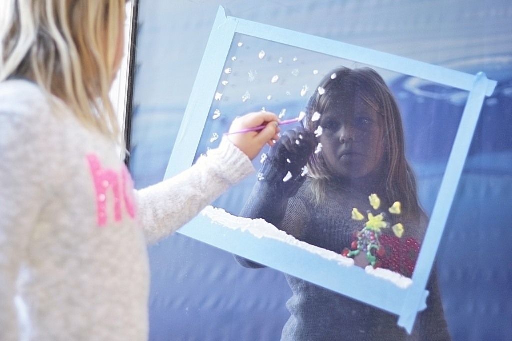 Chloe Bennett, 8, a third grader at Newport Elementary School, helps “Paint the Town” as she creates a snowy Christmas scene on an ExplorOcean window on Wednesday.