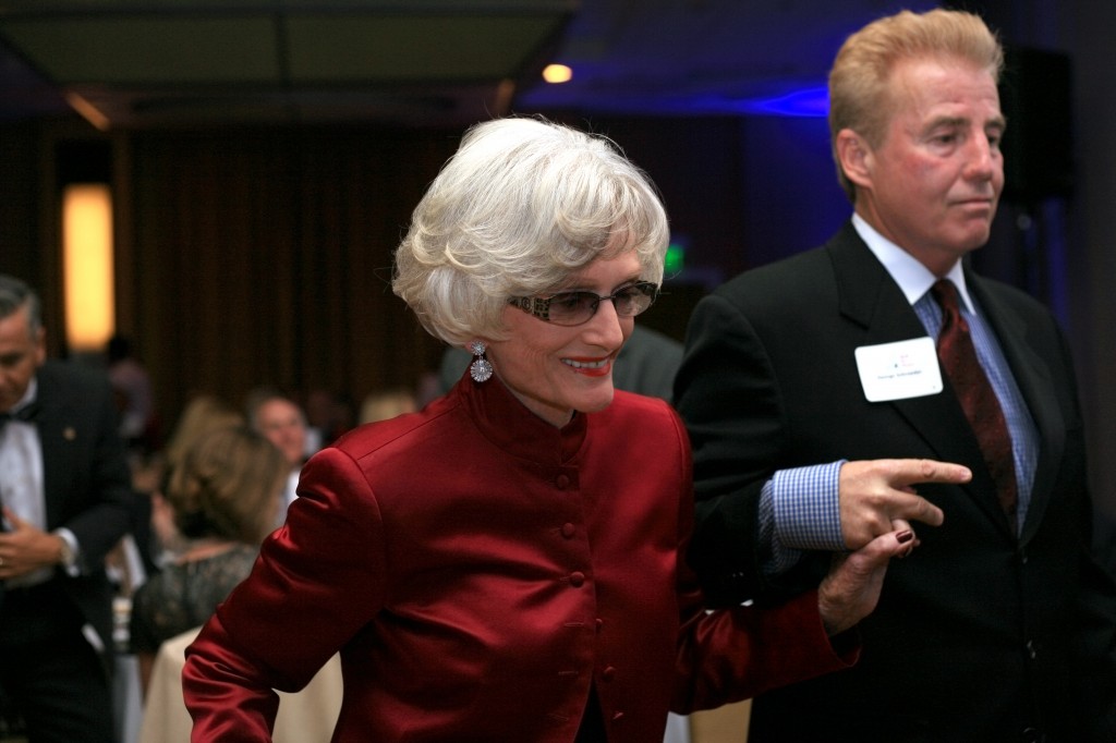 SUN member and event organizer, George Schroeder, helps retired state Senator, Marian Bergeson, up to the stage to receive her SUNshine Award.