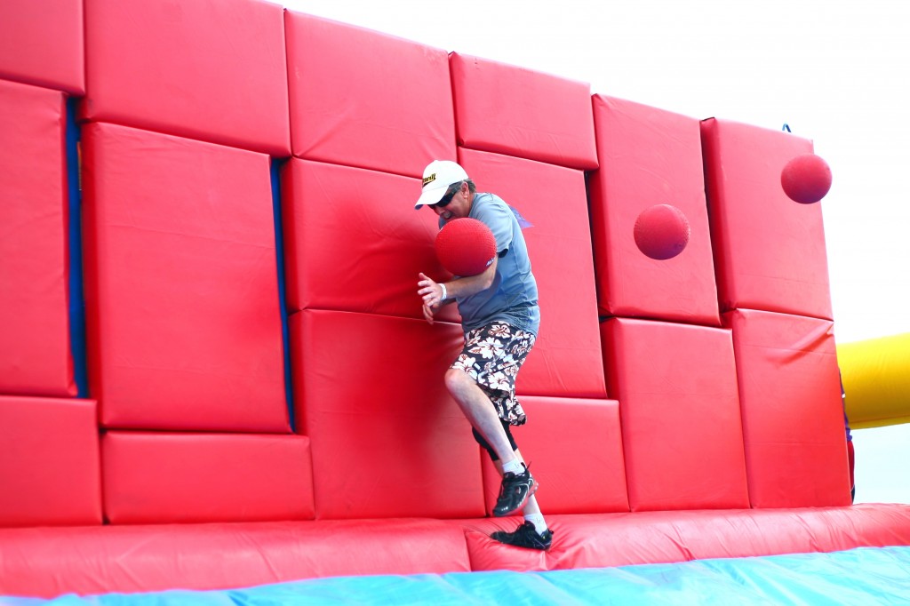 Balls fly as a man tries to cross the fourth obstacle of the fun run, the Whacking Wall.