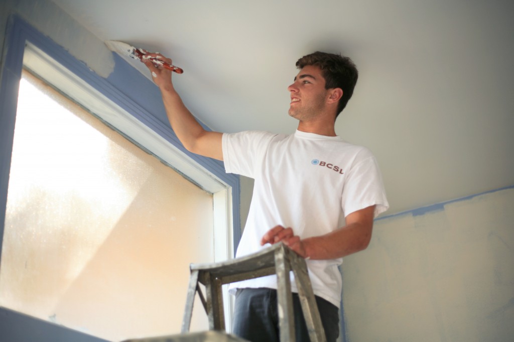 Hunter Wetton, 17, a junior at Corona del Mar High School, paints the ceiling of the foyer to the church.