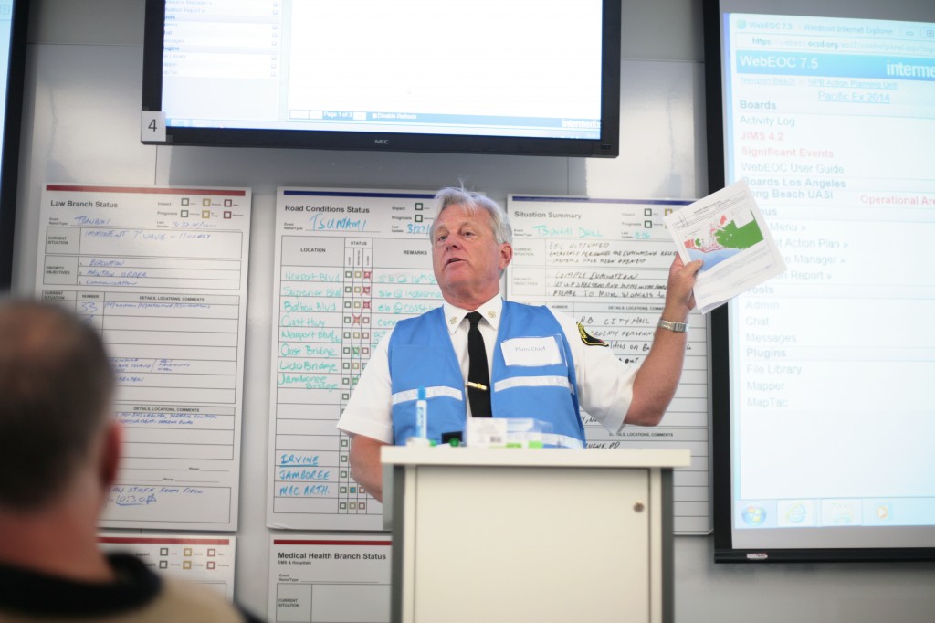 Newport Beach Fire Department Assistant Chief Kevin Kitch briefs city staff members about the Incident Action Plan during Thursday's tsunami drill at the Emergency Operations Center at the Civic Center. Behind him are law and road conditions status boards and a situation summary board that were regularly updated by staff members during the exercise.