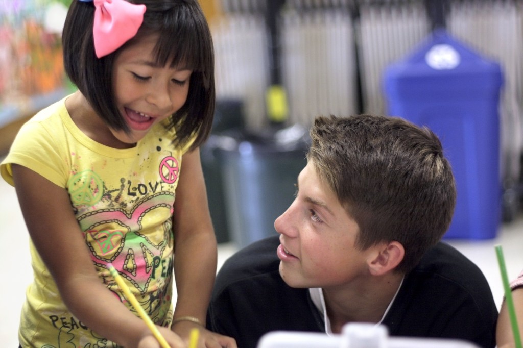 Estephanie Lomas, 6, a first grader in the Project Success program at Adams Elementary School works with National League of Young Men member, Jack Garell, a freshman at Corona del Mar High School, during the league’s Meet the Need visit and school supply delivery on Tuesday. — All photos by Sara Hall ©