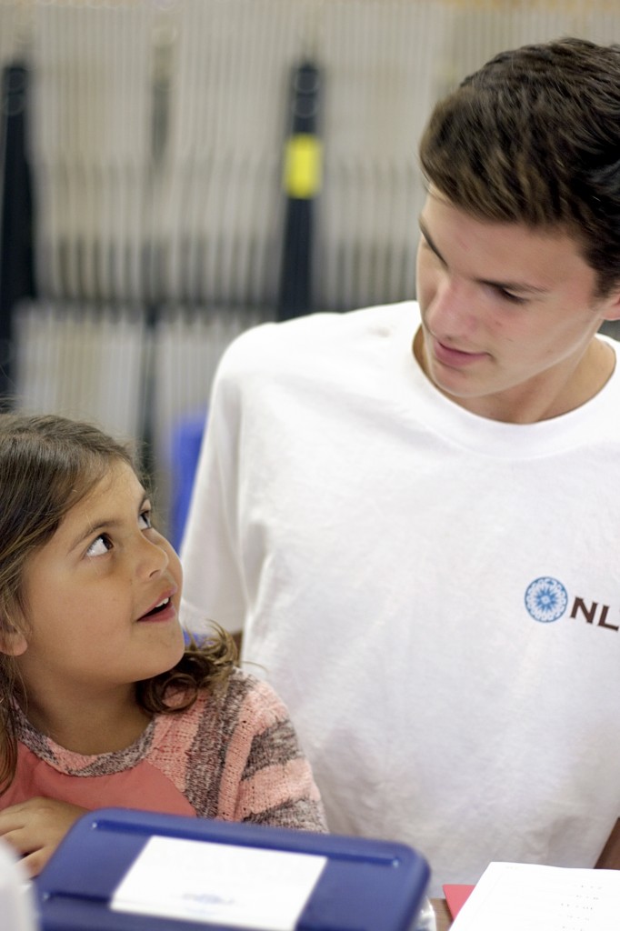 Emilee Menchaca, 6, a first grader in the Project Success program at Adams Elementary School works with National League of Young Men member, Spencer Lawrence, a freshman at Newport Harbor High School, during the league’s Meet the Need visit and school supply delivery on Tuesday.