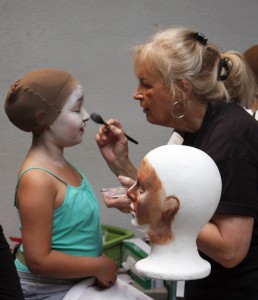 Make up volunteer Flo Vallejo of Newport Beach (right) puts the finishing touches on a cast member  