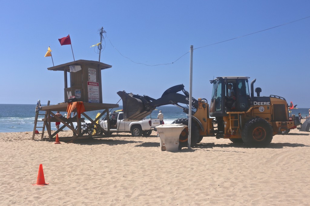 Workers move the lifeguard tower near the Wedge last week after the strong surf washed away sand from the beach.  — Photo by Jim Collins ©