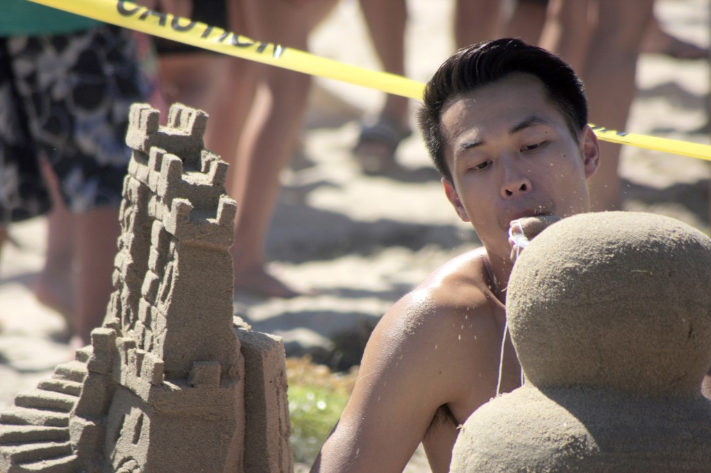 Andy Nguyen of team San Diego Sandcastle Silicate Based Life Forms blows loose sand from his sculpture. The team took home top honors, the Commodores Award of Overall Best Creation. — Photo by Sara Hall ©