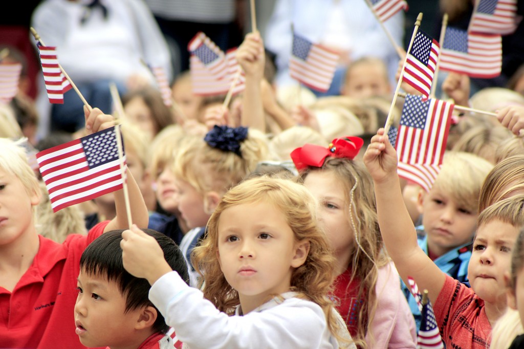 Students at Mariners Elementary School wave flags during a patriotic song on Veterans Day. — Photo by Sara Hall