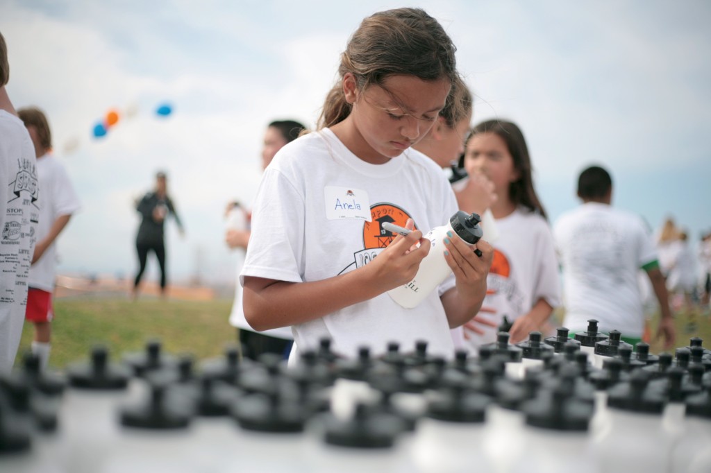 Anela Brown, 10, a Newport El fifth grader, writes her name on a water bottle during the Jog-A-Thon. — Photo by Sara Hall