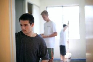 National League of Young Men members Ethan Zimmerman, 16, sophomore at Newport Harbor High School (front), Blake Richter, 15, freshman at NHHS (middle), and Jack Pritchess, 15, freshman at Mater Dei High School, paint one of the rooms at a Human Options housing location last weekend.