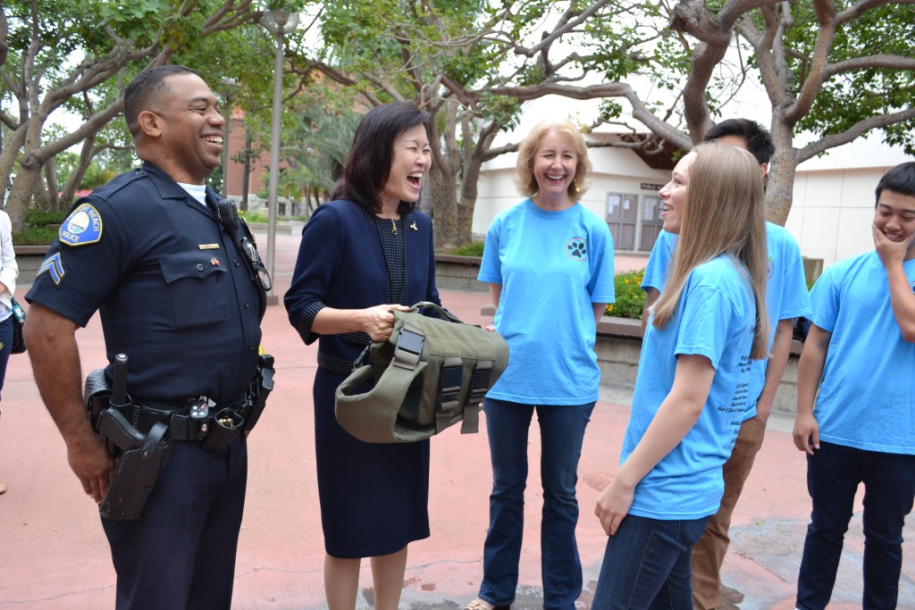 (left to right) Newport Beach Police Department’s School Resource Officer for Corona del Mar High School Vlad Anderson, Orange County Supervisor Michelle Steel, CdMHS Vest-A-Dog club staff advisor Tory Hughes, and CdMHS Vest-A-Dog student founder Jenny Conde smile and talk as they look over one of the vests the club buys for local police K-9 officers before the OC Board of Supervisors meeting on Tuesday in Santa Ana.  — Photo by Darla Conde