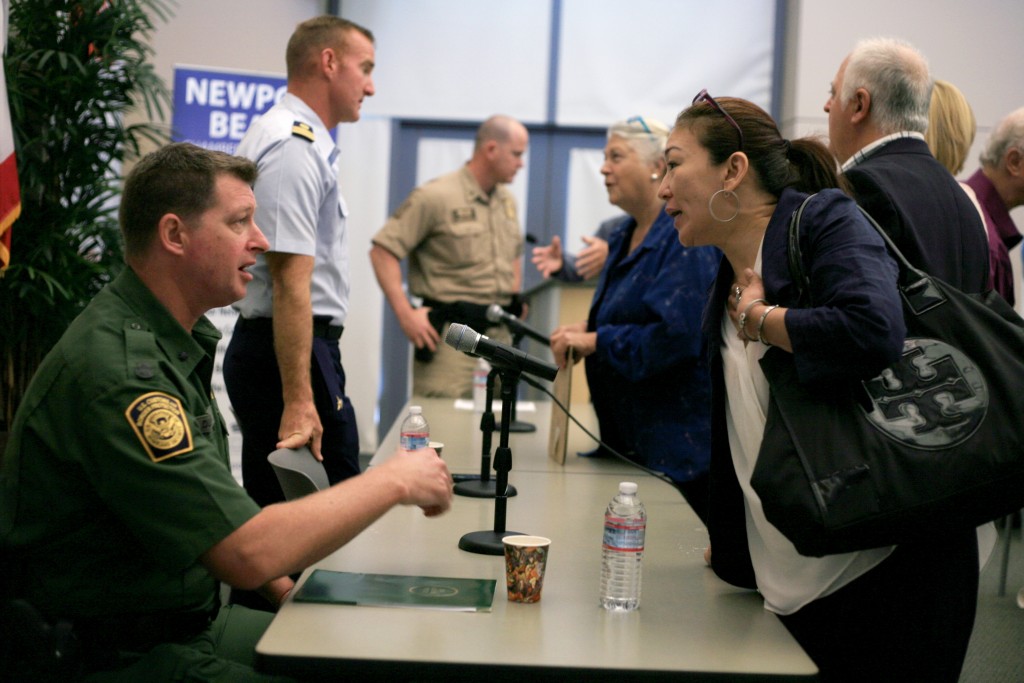 (front left) U.S. Border Patrol agent in charge Mark Dunbar and other Department of Homeland Security officials speak with attendees after the Wake Up! Newport meeting on Thursday. — Photo by Sara Hall ©