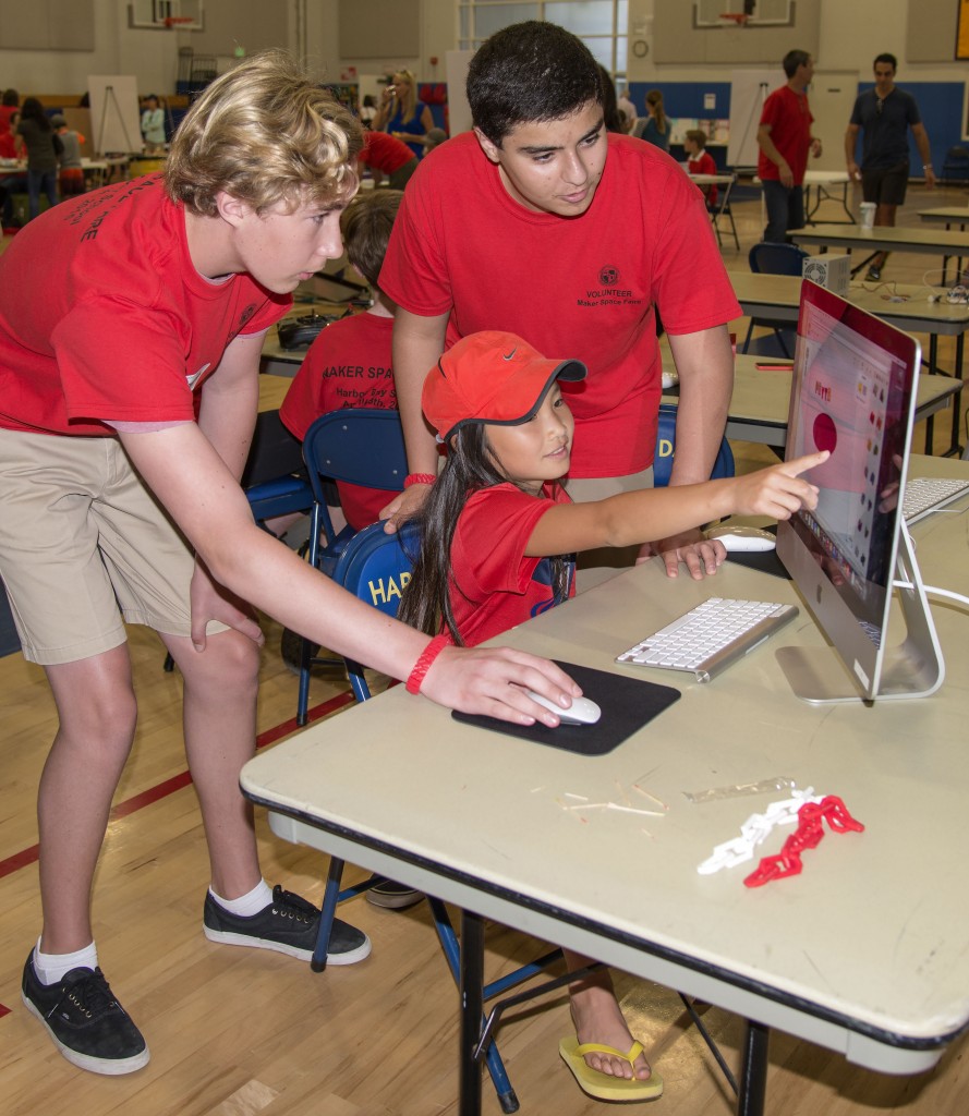 Harbor Day School eighth graders Grant Person (left) and Eamon Nikfas, both 14, help third grader Peyton Vovan, 9, on a project at the 3-D printer booth during the school’s Maker Faire on April 18. — Photo by Charles Weinberg