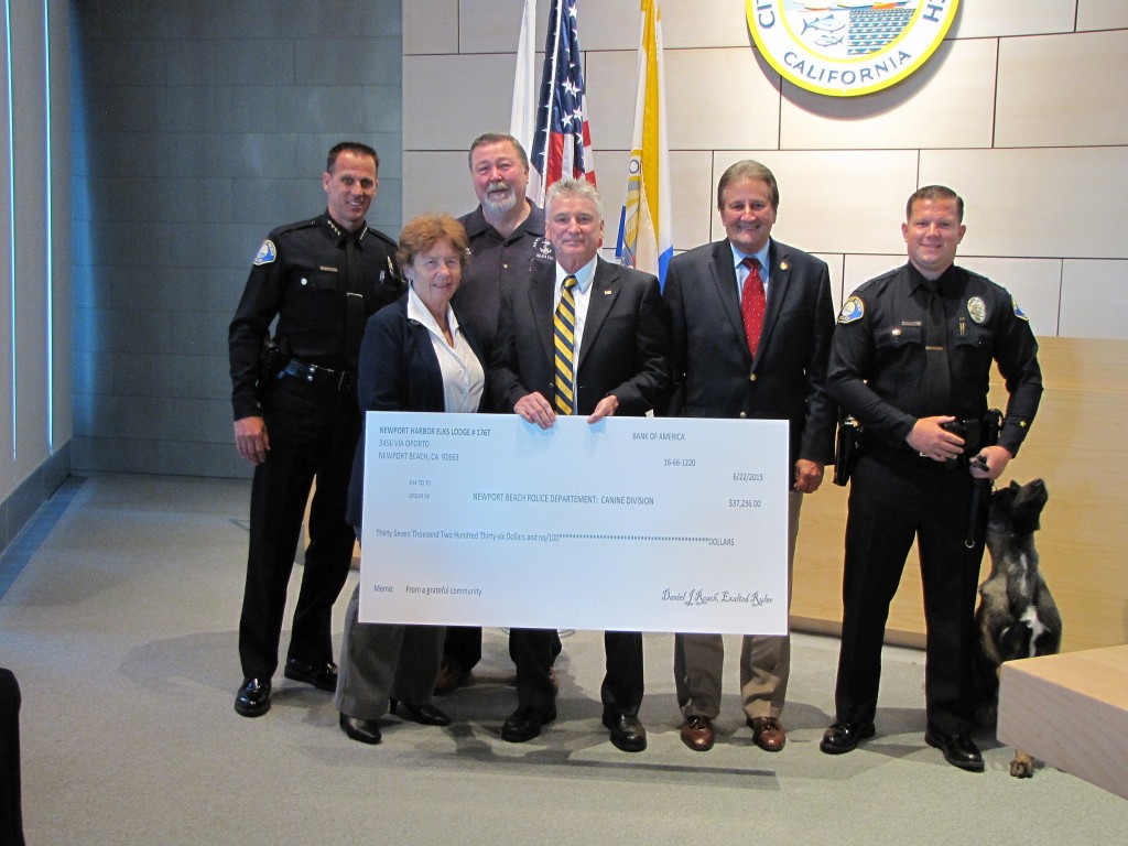(left to right) NBPD Chief Jay Johnson, Newport Harbor Elks Lodge representatives, NH Elks Lodge Exalted Ruler Daniel Roach, Mayor Ed Selich, and Officer Todd Wilson with and Kajo. — Photo courtesy the city of Newport Beach ©