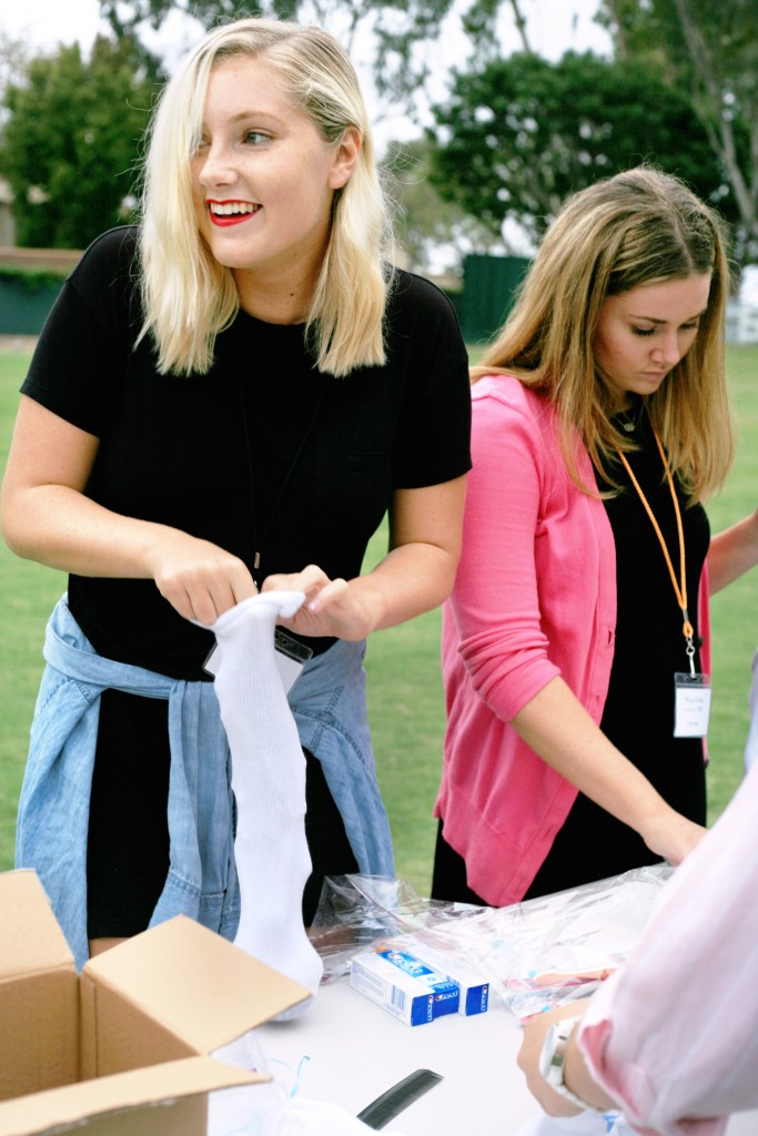 High school seniors Claire Olmstead (left) from Newport Harbor and Abigail Klein from Corona del Mar, both 17, create basic hygiene kits by filling socks with small items like toothpaste and soap. — Photo by Sara Hall ©