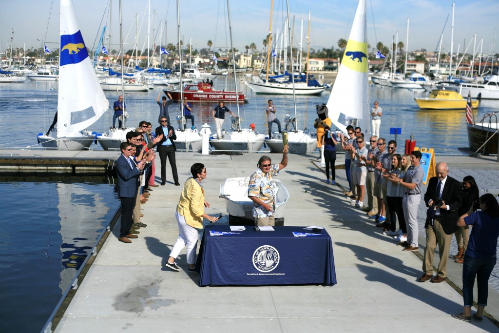 Councilman and Former Mayor Ed Selich holds up a broken champagne bottle after christening the fleet from the University of California, Irvine, sailing program. — Photo by Sara Hall ©