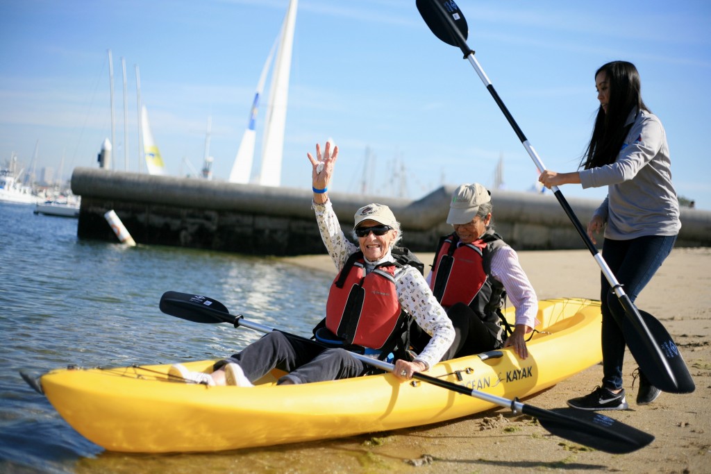 Balboa Peninsula resident Patricia Litten (front, left) and Fountain Valley resident Margie Kim take a kayak out on the bay as University of California, Irvine, boat staffer Kim Tran helps during the Marina Park event. — Photo by Sara Hall ©