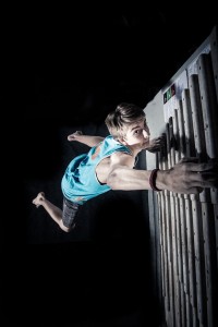 Jordan Keyes climbing a wall ladder using only his arms (photo credit: Olin Burrow).   