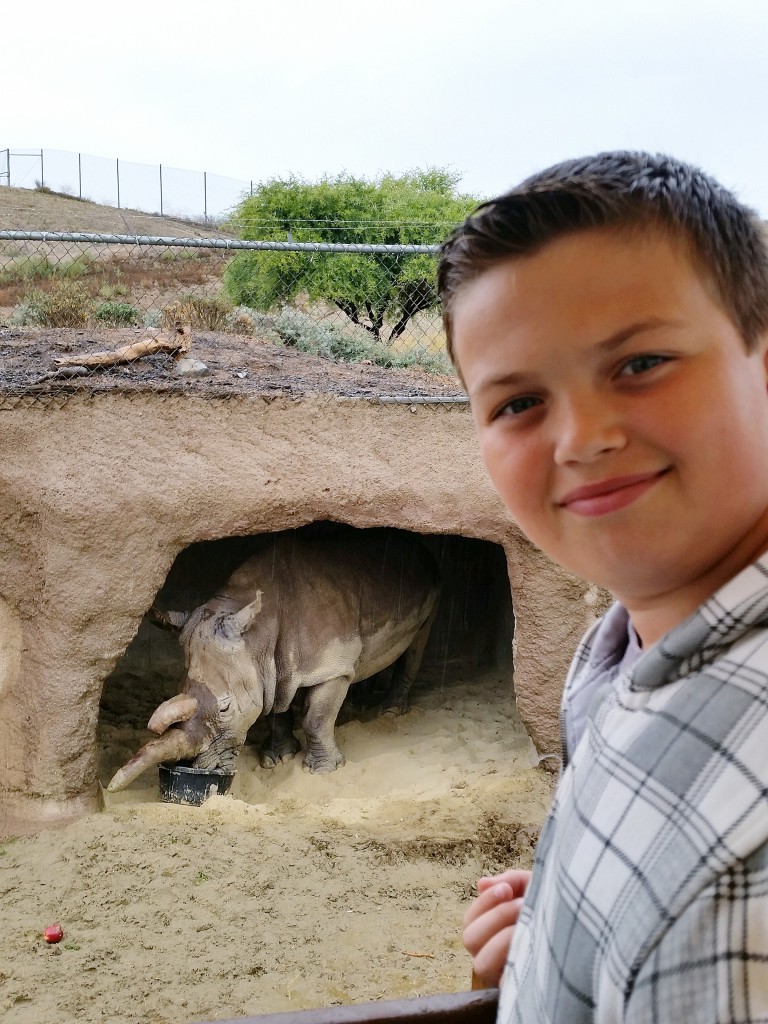 Entrepreneur and wildlife enthusiast Dylan Fryer, 12, a Corona del Mar Middle School seventh grader, with Nola, a northern white rhino, at the San Diego Zoo safari park. — Photo by Michelle Fryer ©