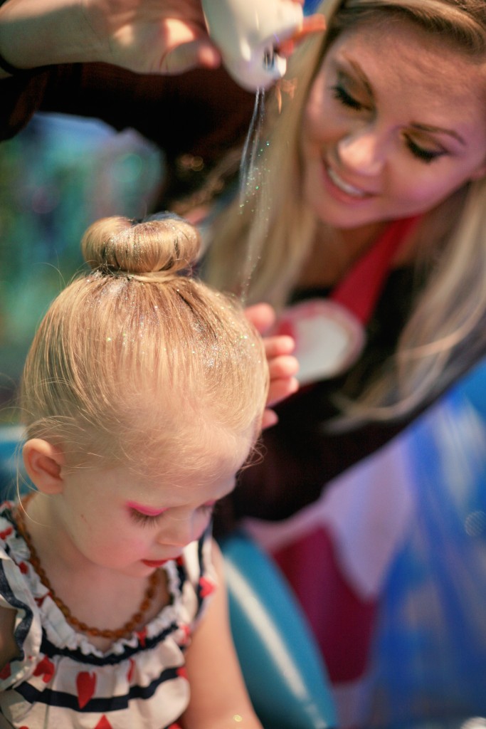 Berlin Martin, 2, gets glitter sprinkled into her hair by her mom, Gillian, in the Jellyfish Salon. — Photo by Sara Hall ©