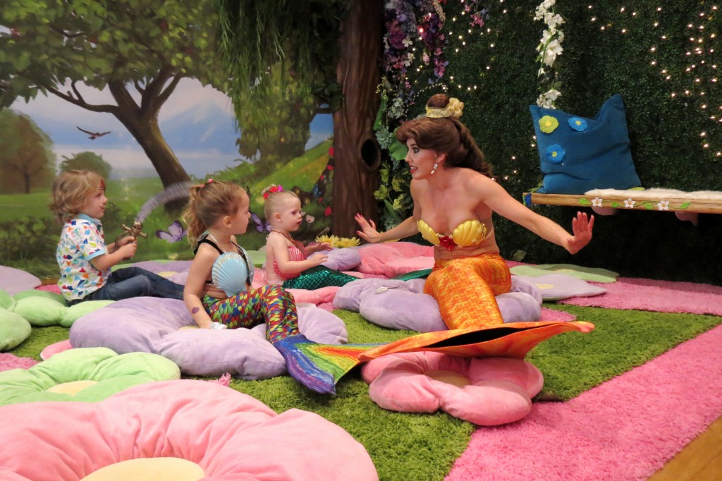 Princess Belle (far right, transformed into a mermaid) tells a story to (left to right) Landon Martin, 4, Skylar Amirpur, 3, and Berlin Martin, 2, dressed up as mermaids and a pirate, during a recent Mermaid Monday at Once Upon an Island on Balboa Island. — Photo by Elizabeth Greenberg ©