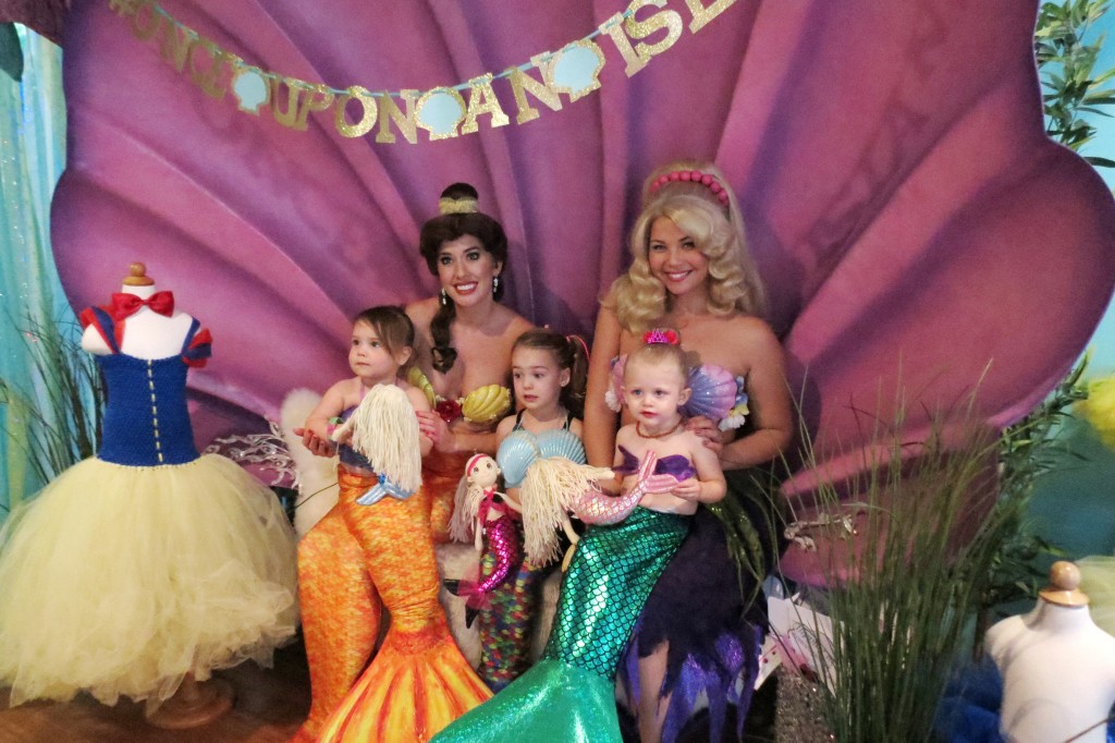 Mini mermaids (left to right) Madeline Unverferth, 2, Skylar Amirpur, 3, and Berlin Martin, 2, pose for photos with Princess Belle (transformed into a mermaid) and Arista mermaid. — Photo by Elizabeth Greenberg ©