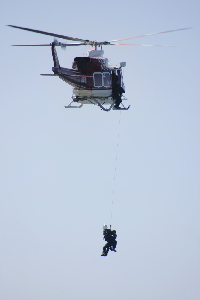 An Orange County Fire Authority helicopter pulls up a rescue worker and a “victim” during the drill. — Photo by Sara Hall ©