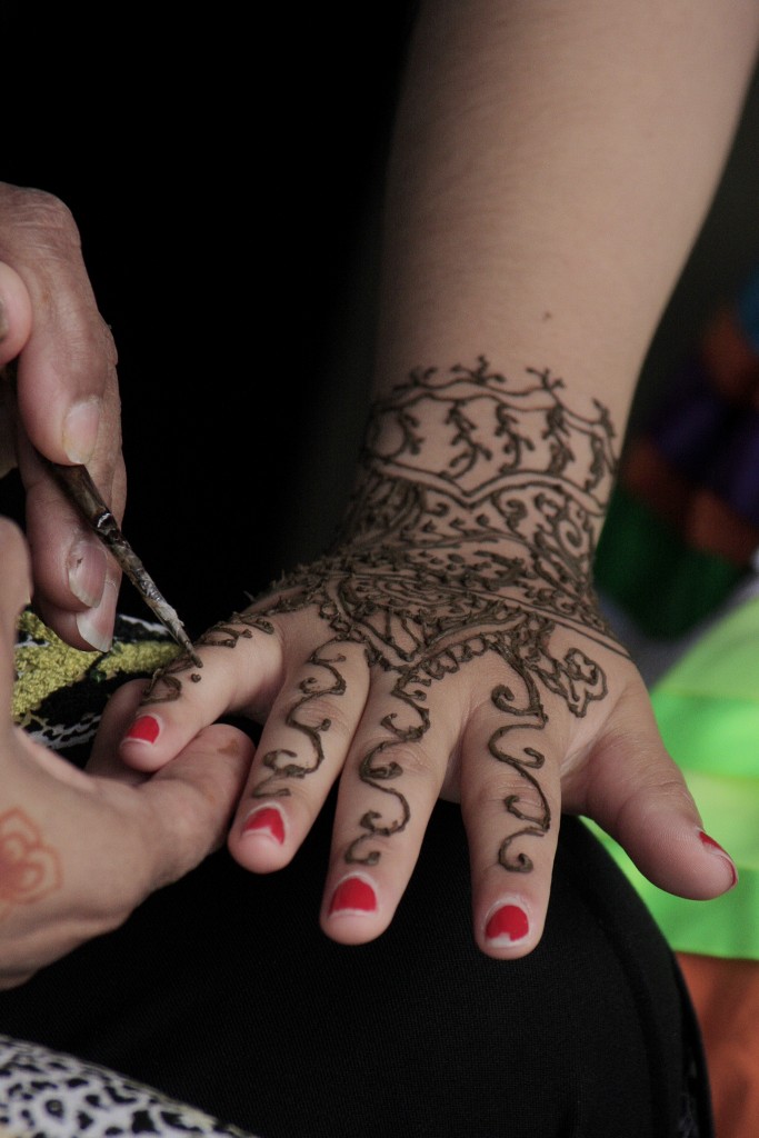 Rana Mohiuddin of Think Outside the Vase draws henna on the hand of Sage sophomore Genesis Gonzalez. — Photo by Sara Hall ©