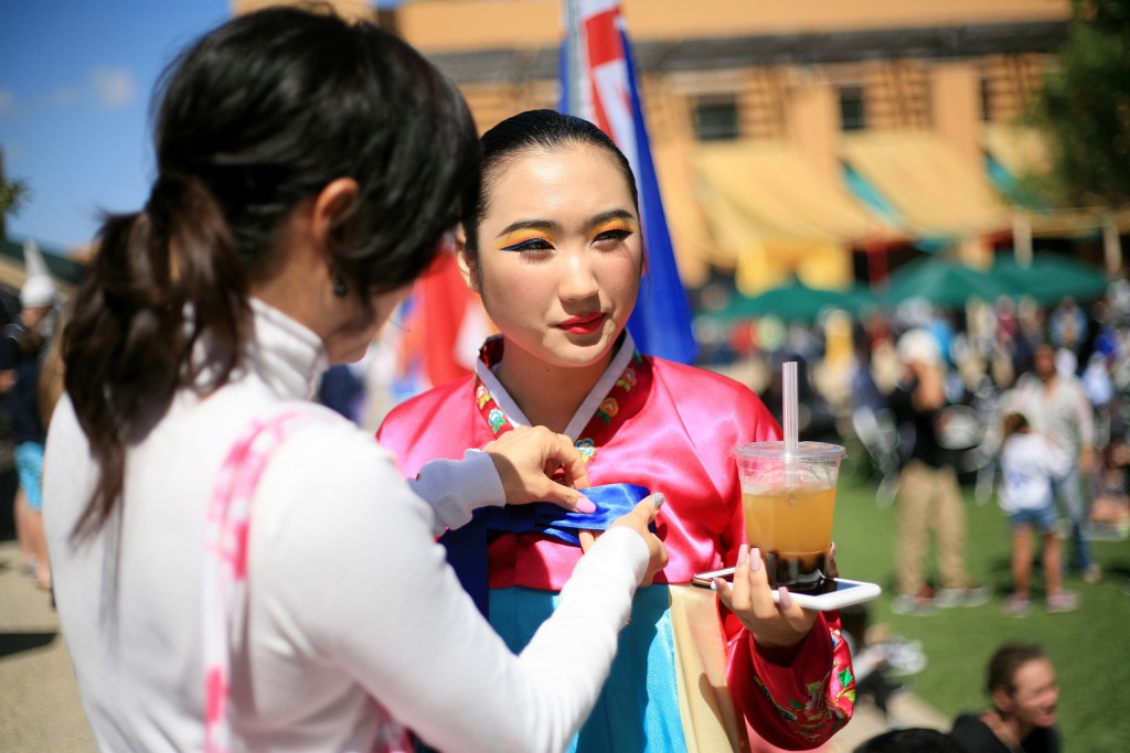 A Korean Nongak dancer from KAYPA gets her bow adjusted and enjoys a drink before heading on stage to perform. — Photo by Sara Hall ©